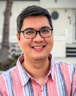 Photo of author facing the camera. He's wearing eyeglasses, and a salmon pink shirt with vertical blue and gray stripes.